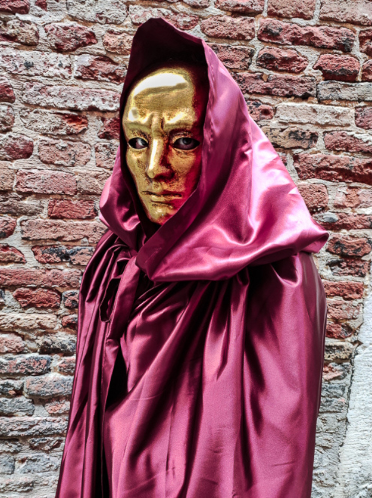 A red-satin-cloak-figure on a street in Venice.