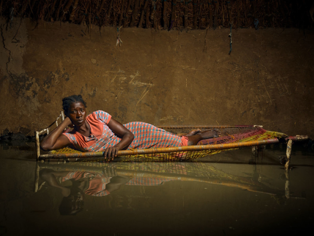 Nyapini Yiel (23) lies on her broken bed inside her flooded home.  